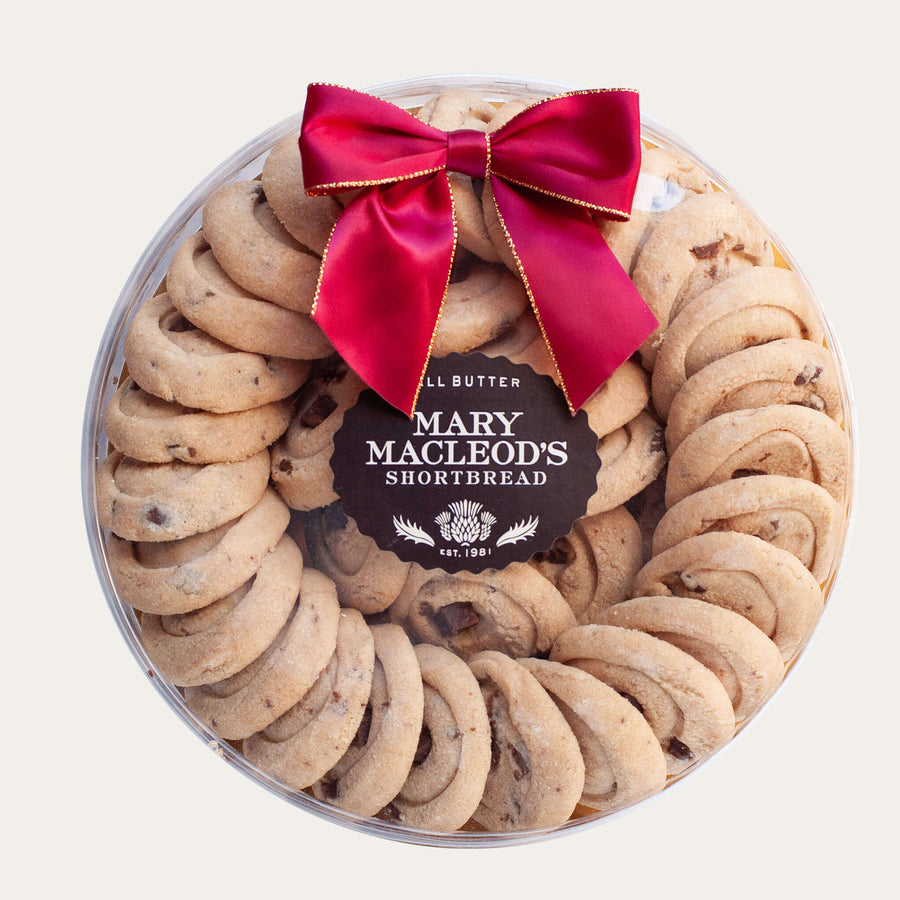 9 Inch Clear Transparent Round package of Mary Macleod's Shortbread with 36 premium artisanal gourmet signature chocolate crunch all-butter shortbread cookies, accented with our holiday red bow, premium holiday Christmas gift 