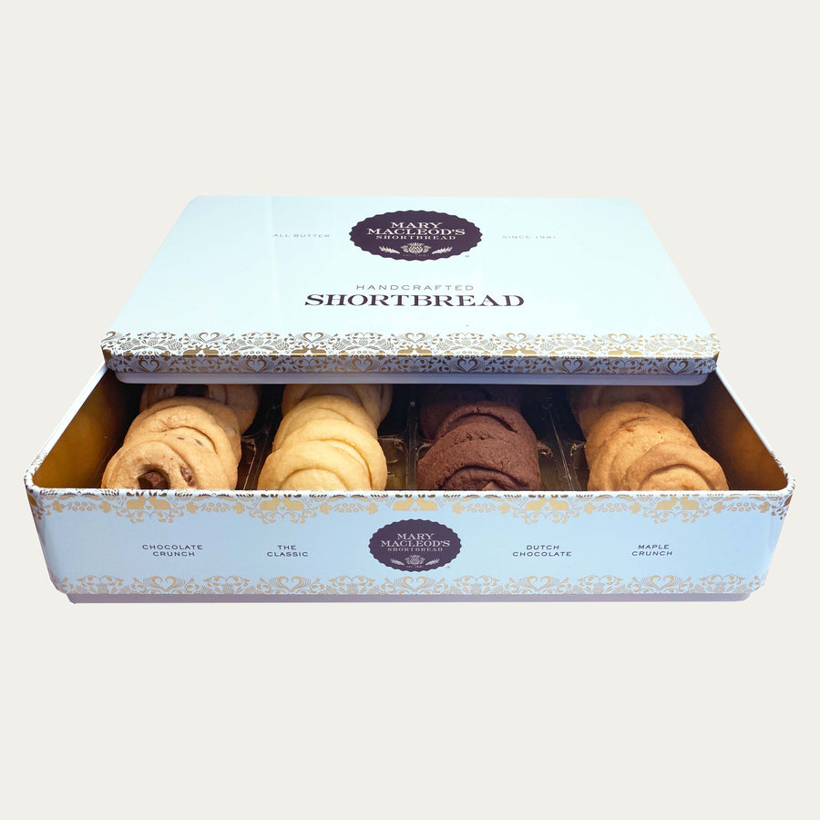 Image of Mary Macleod's Shortbread signature blue stackable cookie tin, brimming with an assortment of buttery shortbread cookies in classic, chocolate crunch, Dutch chocolate, and maple crunch flavours. Elevate your taste experience with 24 delectable cookies crafted with rich, creamy butter. Perfect for gifting or savouring your own indulgence. Plain background. 